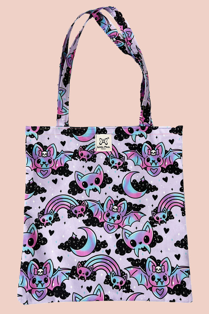a pastel purple tote bag with cute bat design with clouds and love hearts. Shown on a peach coloured background