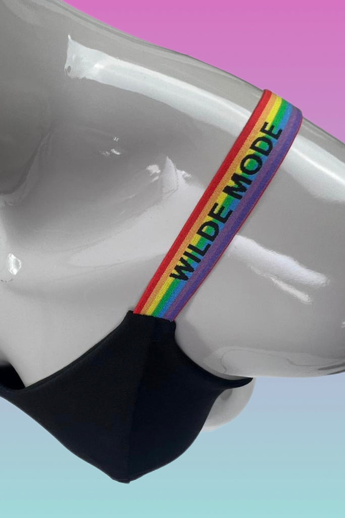 Close up of Wilde Mode Adjustable Slider Bra Straps in rainbow, shown on a mannequin. The straps are rainbow striped with 'Wilde Mode' written across in black.