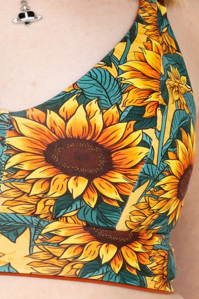 Close up of Sunflower Field Comfort Bra shown on a model facing the camera. The print is a yellow background with big yellow sunflowers with a brown centre and green leaves. 