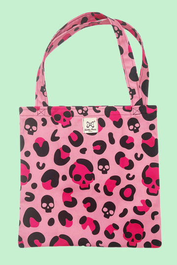 a pink organic cotton tote bag with hot pinkand black leopard print and skull design. Shown on a mint green background