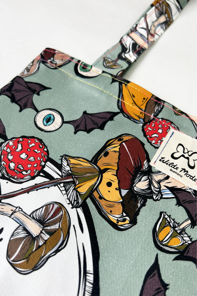 A mint green coloured tote bag with creepy mushroom print with skulls and eyeballs with bat wings